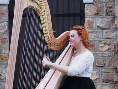 Christy-Lyn playing pedal harp in front of a stone building