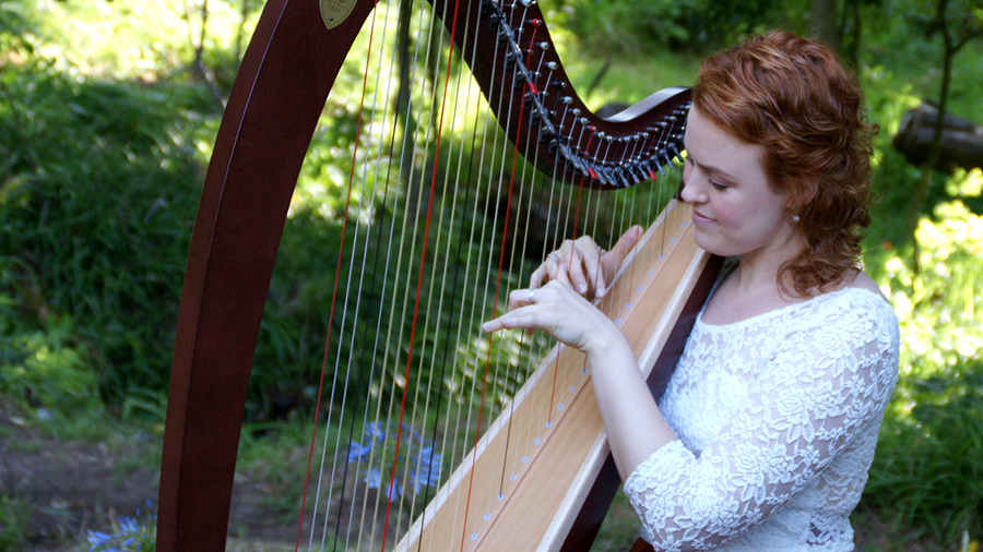 Christy-Lyn playing lever harp in sunlit garden