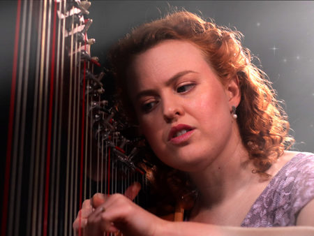Christy-Lyn playing a harp in a dark room
