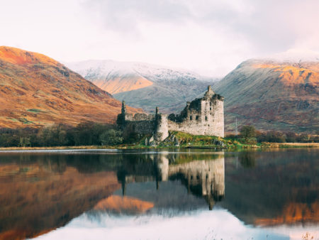 Castle across a body of water with mountains behind