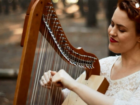 Christy-Lyn playing a harp in a forest