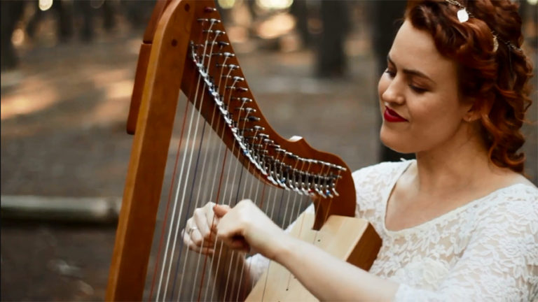 Christy-Lyn playing a harp in a forest