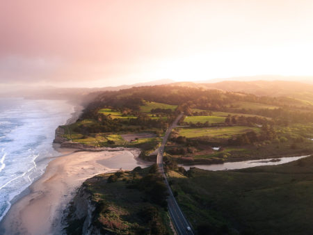Landscape image of the beach and green rolling hills at sunset
