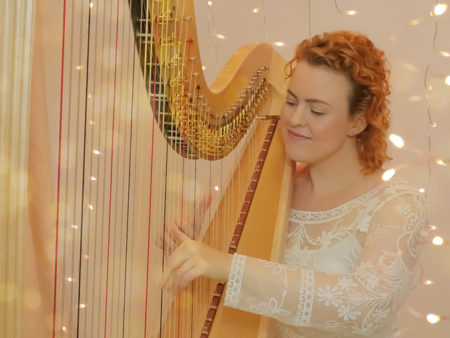 Christy-Lyn playing a lever harp with twinkling lights