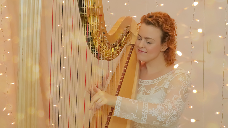 Christy-Lyn playing a lever harp with twinkling lights